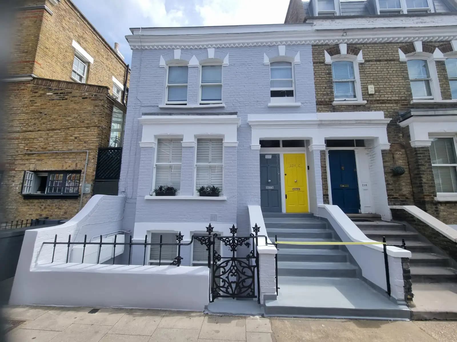 Image of two-story houses with a blue door and yellow trim, under construction or renovation. Stairs are visible,...