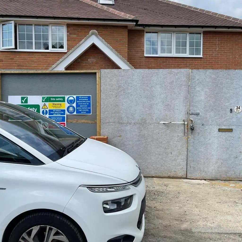 A white car parked in front of a house with construction barriers and a sign, on a cloudy day.
2. The image matches...