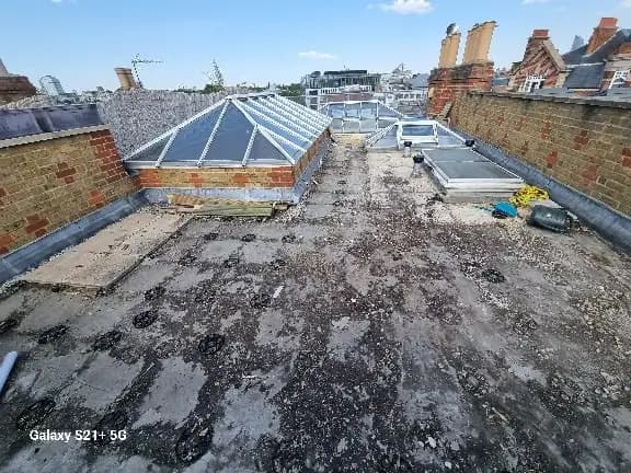 The image depicts a rooftop area undergoing renovation or maintenance. It features exposed roofing materials, patches...